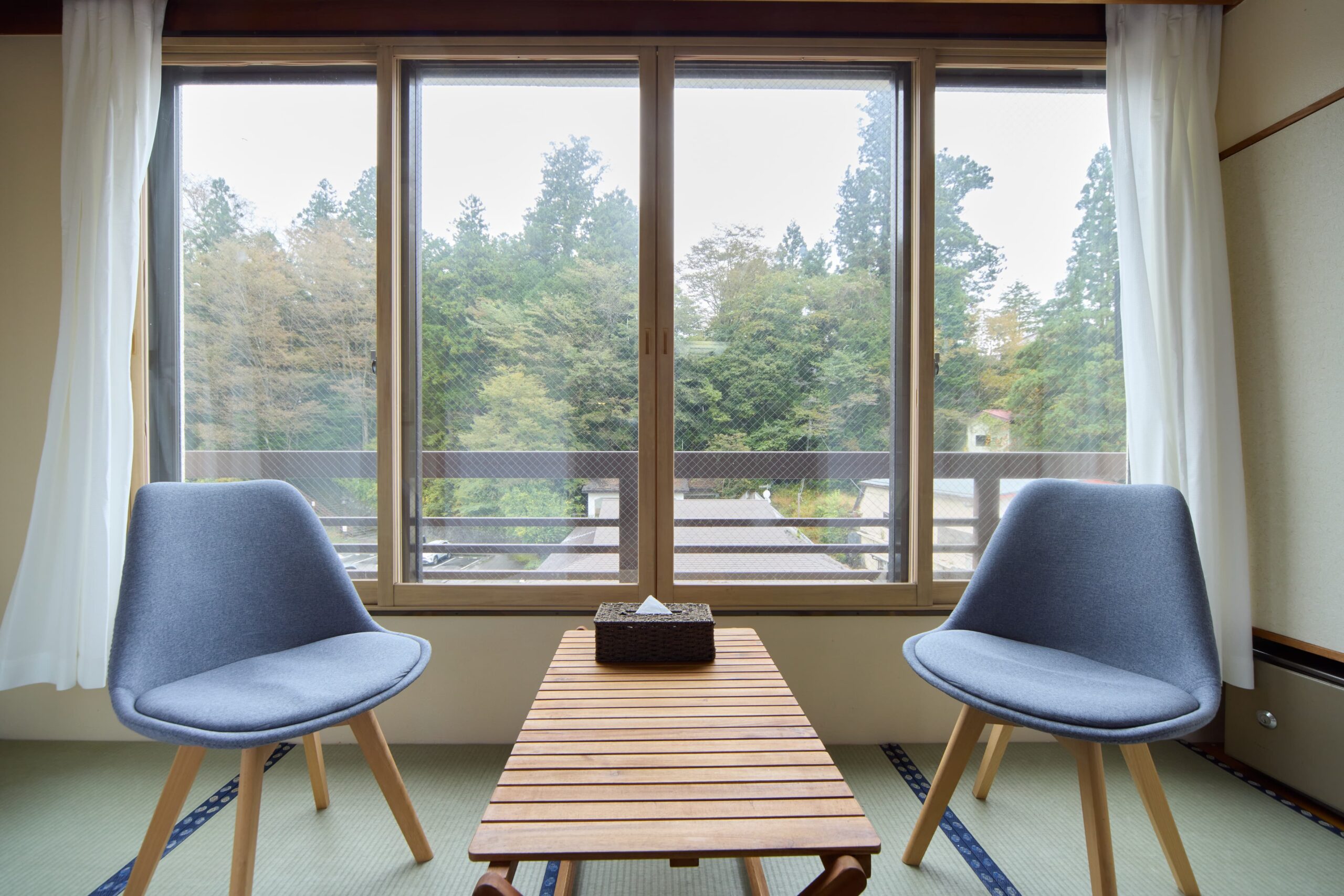 カーテンを開けた椅子とテーブルが置いてある客室