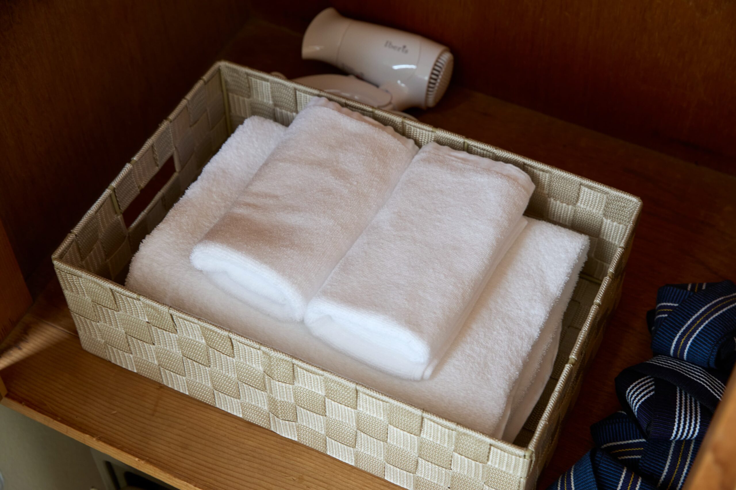 丁寧に畳まれたフェイスタオルとバスタオル、ヘアドライヤーなど
